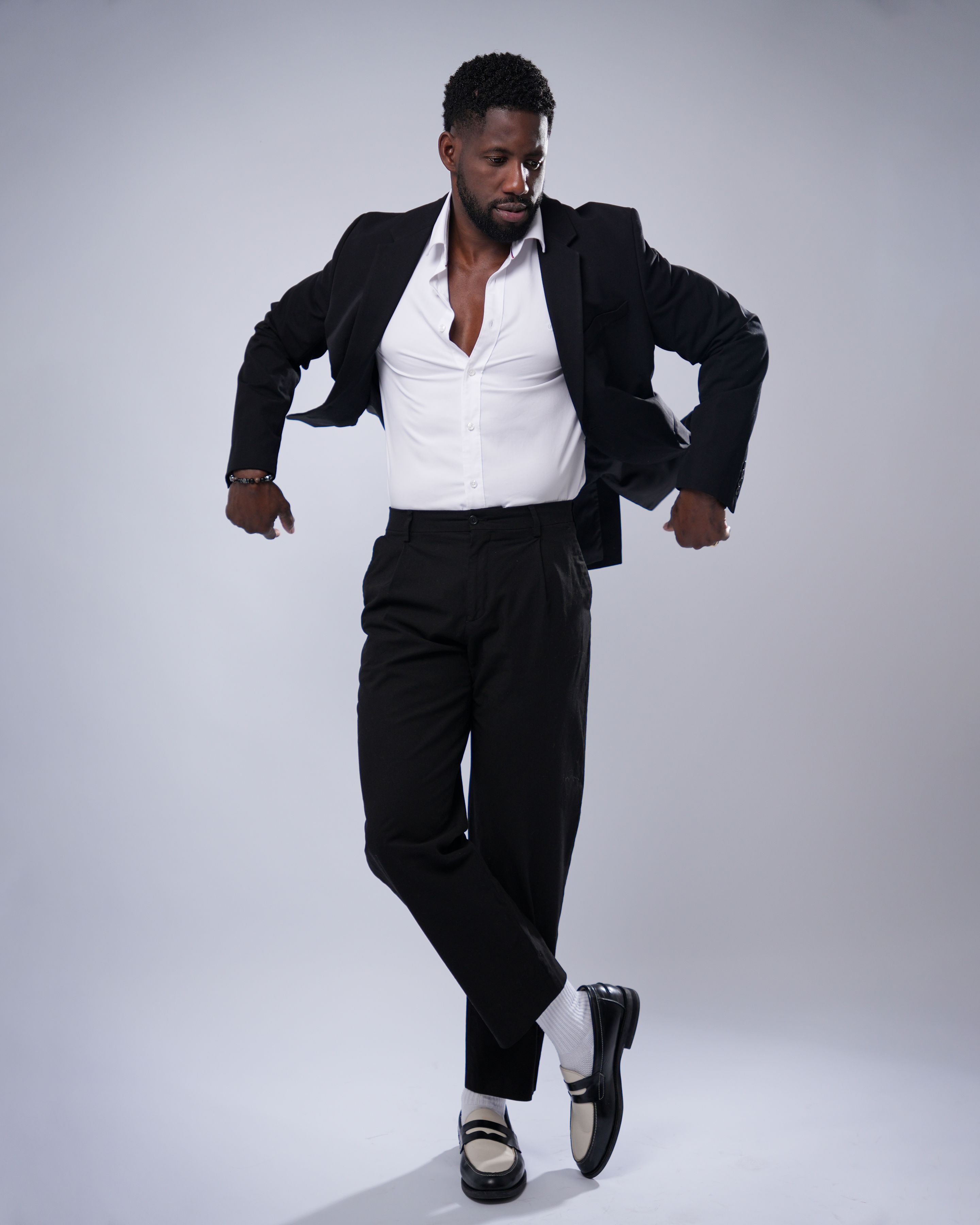 Retrato editorial de Lázaro DCuba con traje negro y camisa blanca